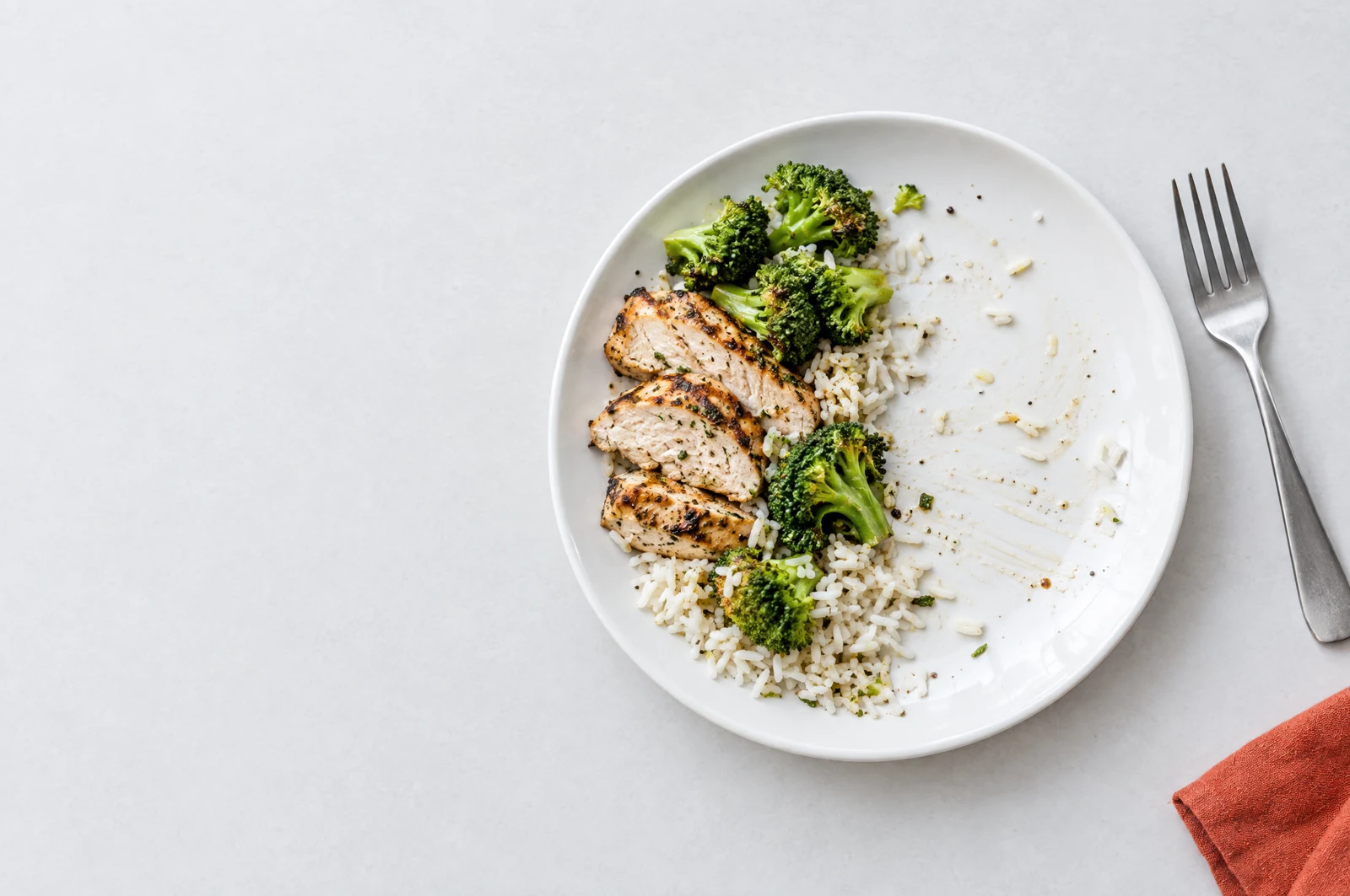 Illustrative half-eaten chicken, rice and broccoli plate